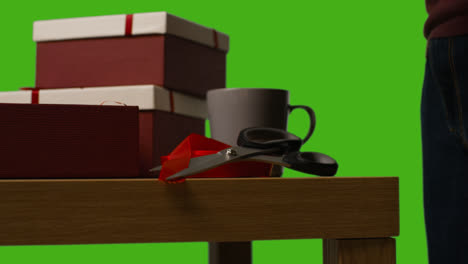 Close-Up-Of-Man-Putting-Present-Into-Gift-Wrapped-Box-On-Table-Shot-Against-Green-Screen-2